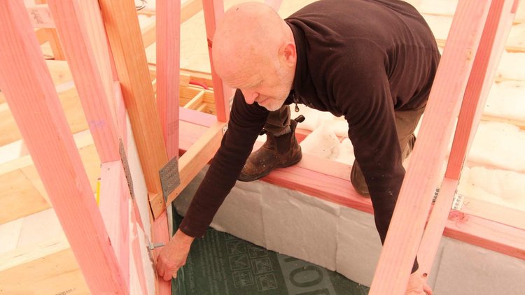 Wellington Retrofit House - A man installing DASATOP<sup>®</sup> Intelligent Air Barrier to wall frames