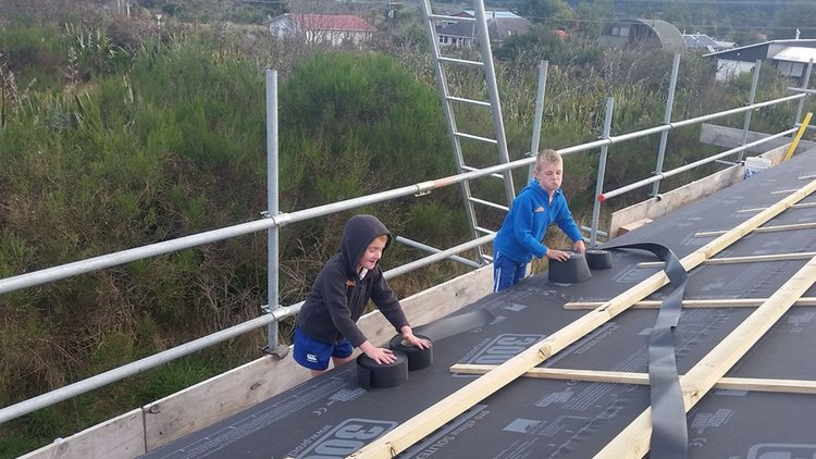 National Park Village Ski Hutt - Two kids playing with sealing tapes on the roof covered with SOLITEX MENTO<sup>®</sup> 3000 connect