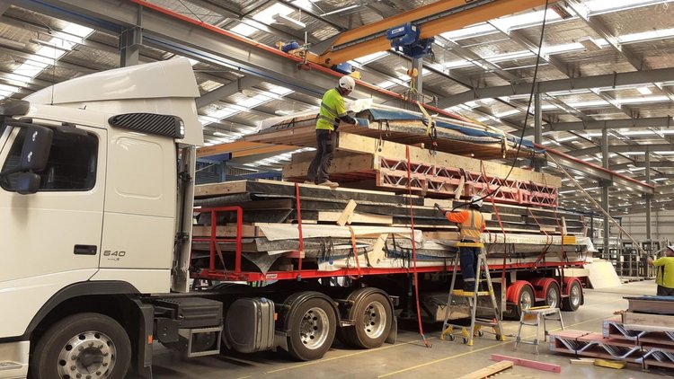 Waihi Passive House - Two builders load prefabricated wall panels onto a truck.