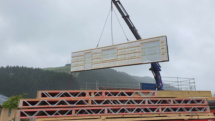 Waihi Passive House - Crane loading prefabricated wall panels onto a truck.