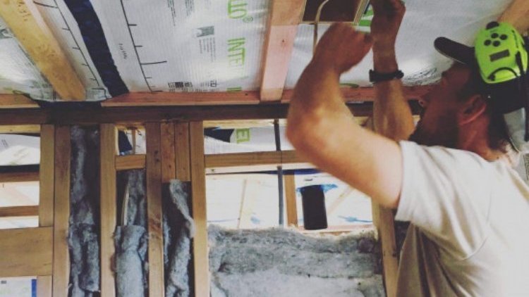 Raglan House - Man installing INTELLO<sup>®</sup> Intelligent Air Barrier on the wall